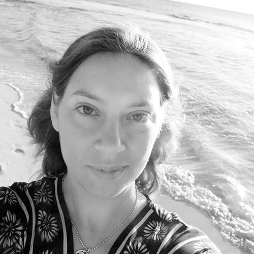 A black-and-white photo of the author standing on a beach and looking up at the camera